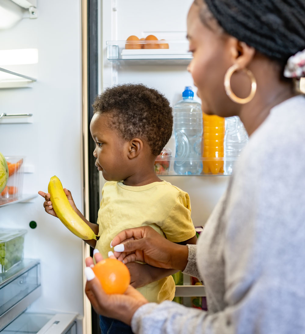 Child holding banana, adult offering an orange