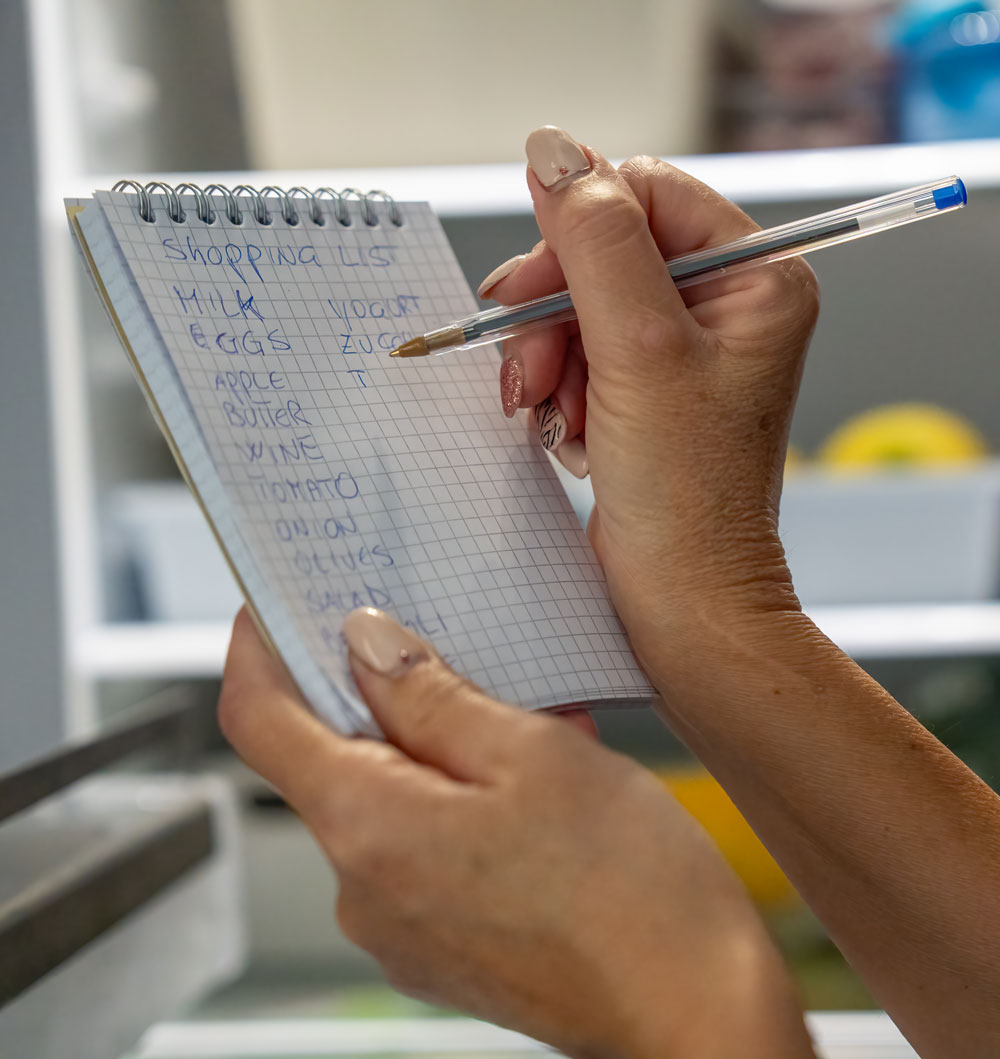Hand writing shopping list with pen on notepad