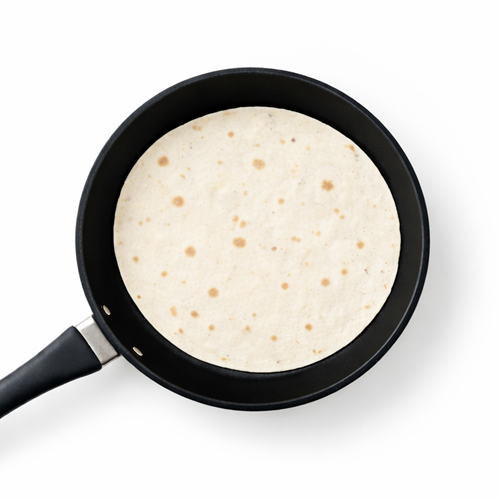 Tortilla warming in a black frying pan.
