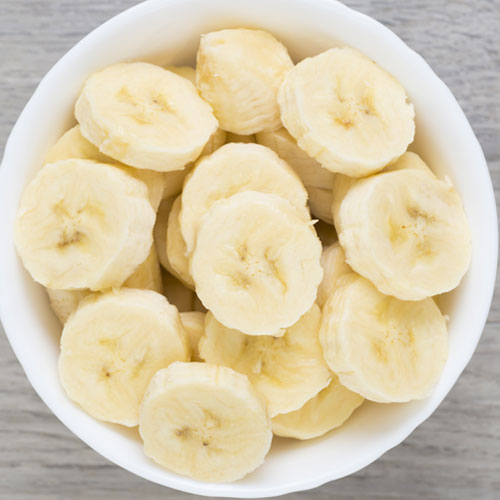 Sliced bananas in a white bowl on table
