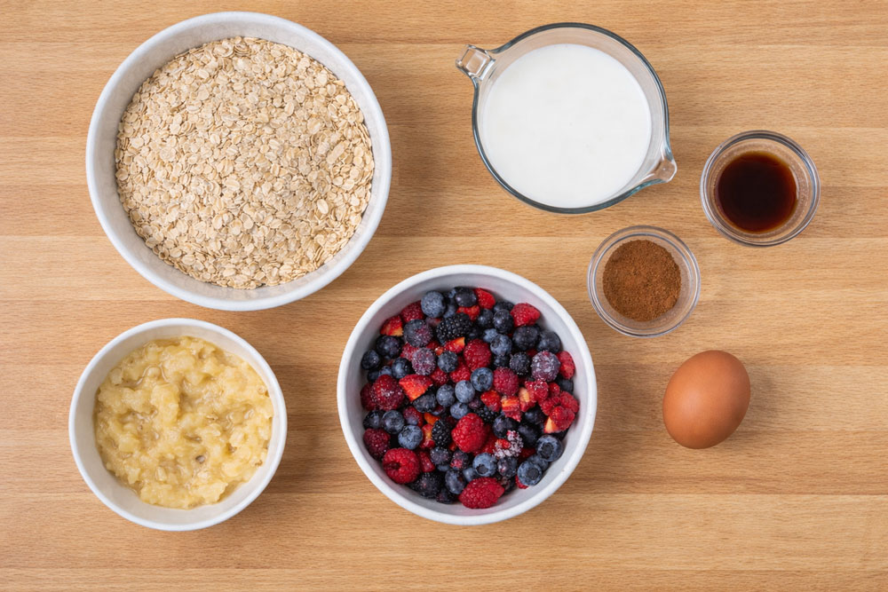 Oatmeal, milk, berries, banana, egg, cinnamon on table
