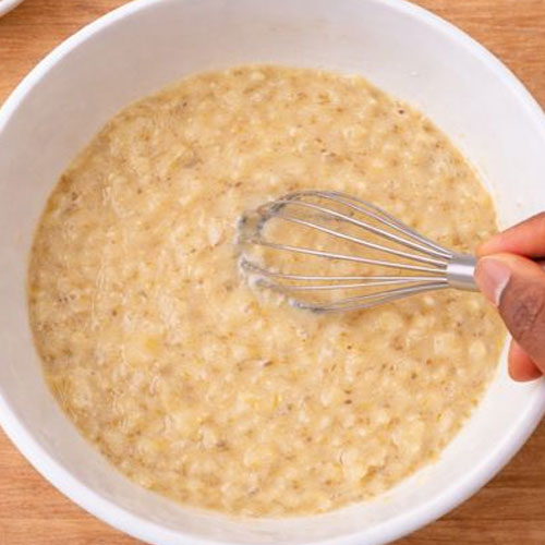 Whisk stirring oatmeal in a white bowl